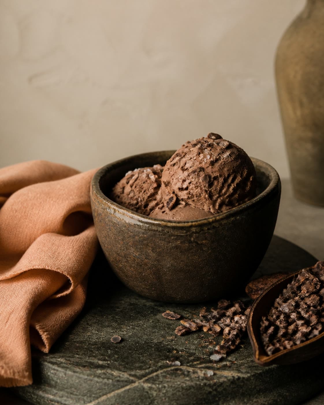 Two dark scoops in a glazed brown bowl on a green stone slab